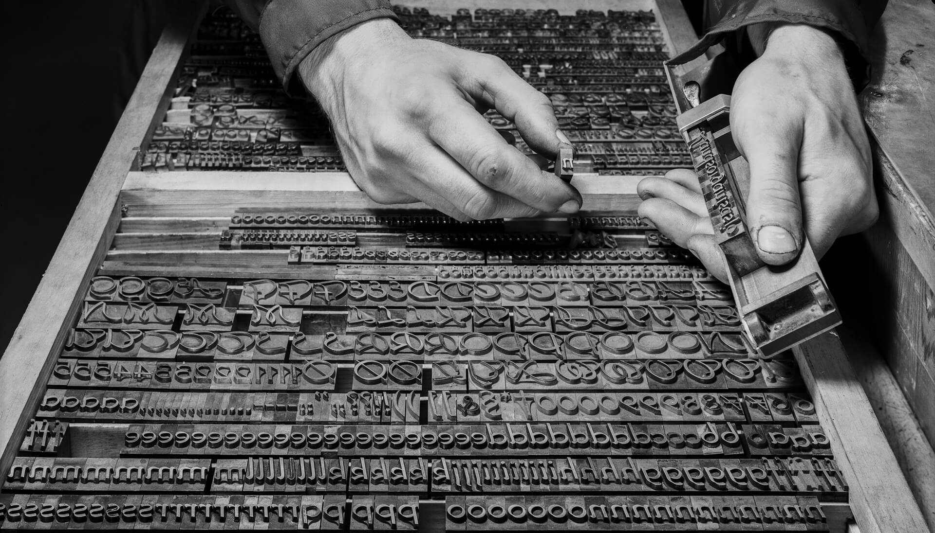 fotografi av arbeidshender med settekasse i sort hvitt